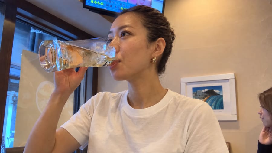 Miyu sipping a tall highball at a cozy bar table