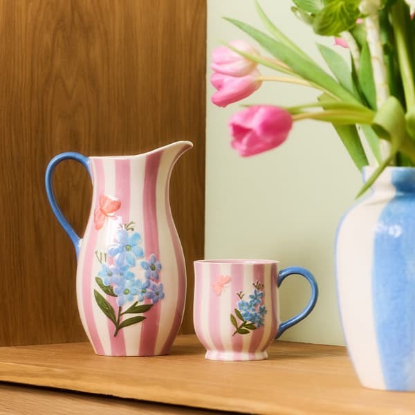 Jarra y taza con rayas rosas con detalles de flores y mariposas