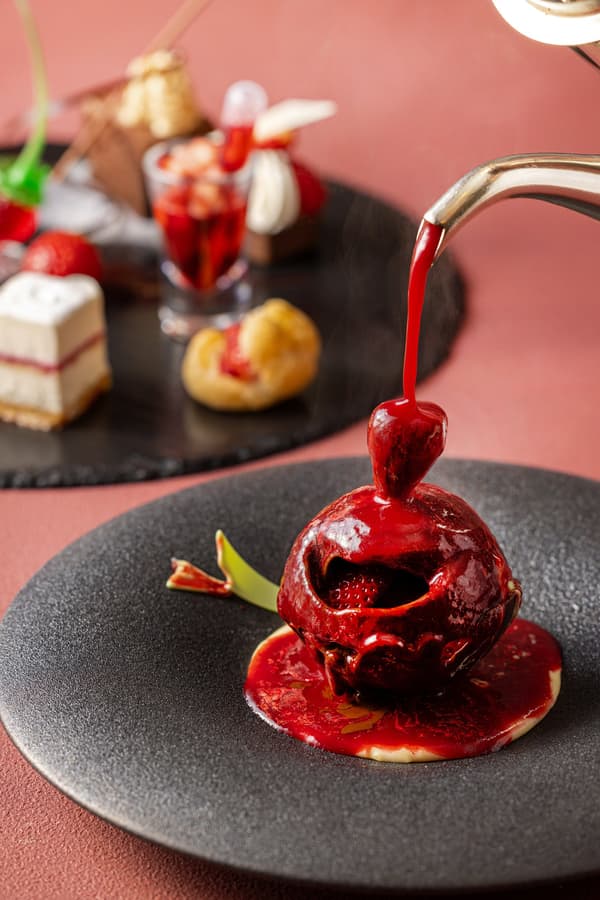 Cúpula de chocolate con fresa y salsa inglesa, servida con salsa de bayas caliente