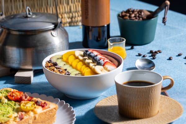 Café preparado en fogata servido junto con tostadas de pizza y un tazón de cacao